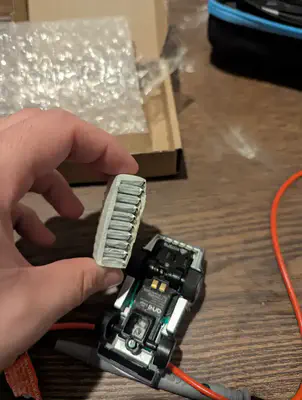 A small batch of replacement pouch batteries held side by side above an upside-down car.